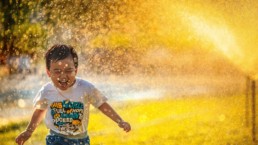 gutt løper gjennom en vannspreder